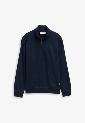 Tmavomodrý sveter s krátkym zipsom vyrobený z jemnej látky, s dlhými rukávmi, polozipsovým predným zapínaním a diskrétnou logom nášivkou na spodnom leme.