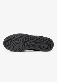 Fekete gumi sneaker talp, bonyolult bordázattal és kör alakú részletekkel, az oldalán "PEGADOR" márkázva.
