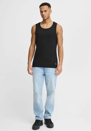 Svart bomullstopp med rund halsringning, bärs med ljusblå denimjeans och svarta sneakers. Inga synliga mönster eller logotyper.