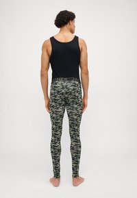 Black sleeveless top paired with fitted, camouflage-patterned leggings in shades of green and gray, featuring a textured elastic waistband.