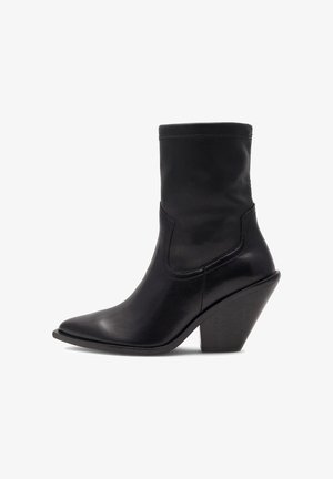 Bota de tobillo de cuero negro con punta afilada, tobillo estrecho y tacón de cuña geométrico. Textura lisa y detalles mínimos de costura.