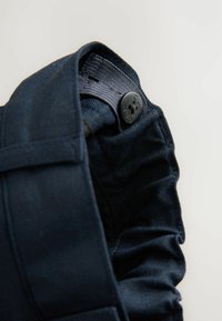 Tumesinine denimpindel omadab tekstuuri pinnaga ja sujuva sisepinnaga. Must nupp dekoratiivse kujundusega kinnitab vööosa.