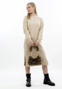 Beige adīšanas svārku kleita ar garām piedurknēm, sānu š�ķirbm, kombinēta ar leoparda raksta rokassomu un melniem potītēm zābakiem.