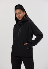 Veste imperméable noire avec un col haut, deux poches latérales zippées et des poignets ajustables. Dispose d'une fermeture éclair à l'avant pour un confort d'utilisation.
