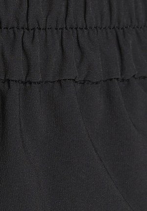 Black fabric with a soft texture features elastic gathering at the waistband. The material is lightweight and smooth with slight sheen.