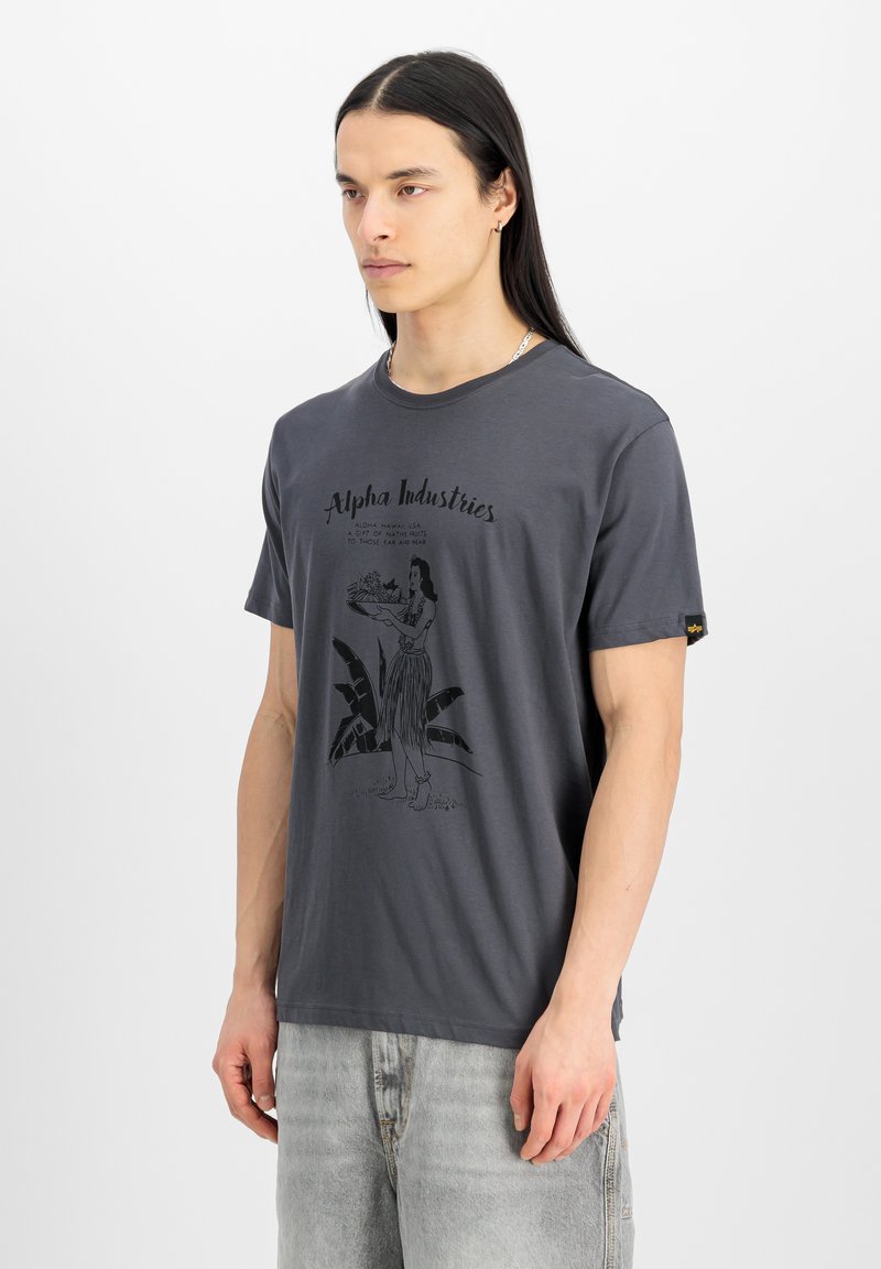 Grå bomull T-shirt med en svart grafisk tryck av en kvinna som håller frukt omgiven av tropiska blad. Korta ärmar och rundad halsringning.