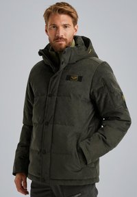 Gevoerde donkergroene jas met een rits- en knoopsluiting, capuchon, zijzakken en een gestructureerde stof. Beschikt over een patchdetail op de borst.