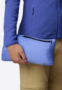 Borsa pieghevole azzurro chiaro con chiusura a zip, tenuta in una mano. Texture liscia, design leggero, adatta per riporre e trasportare.