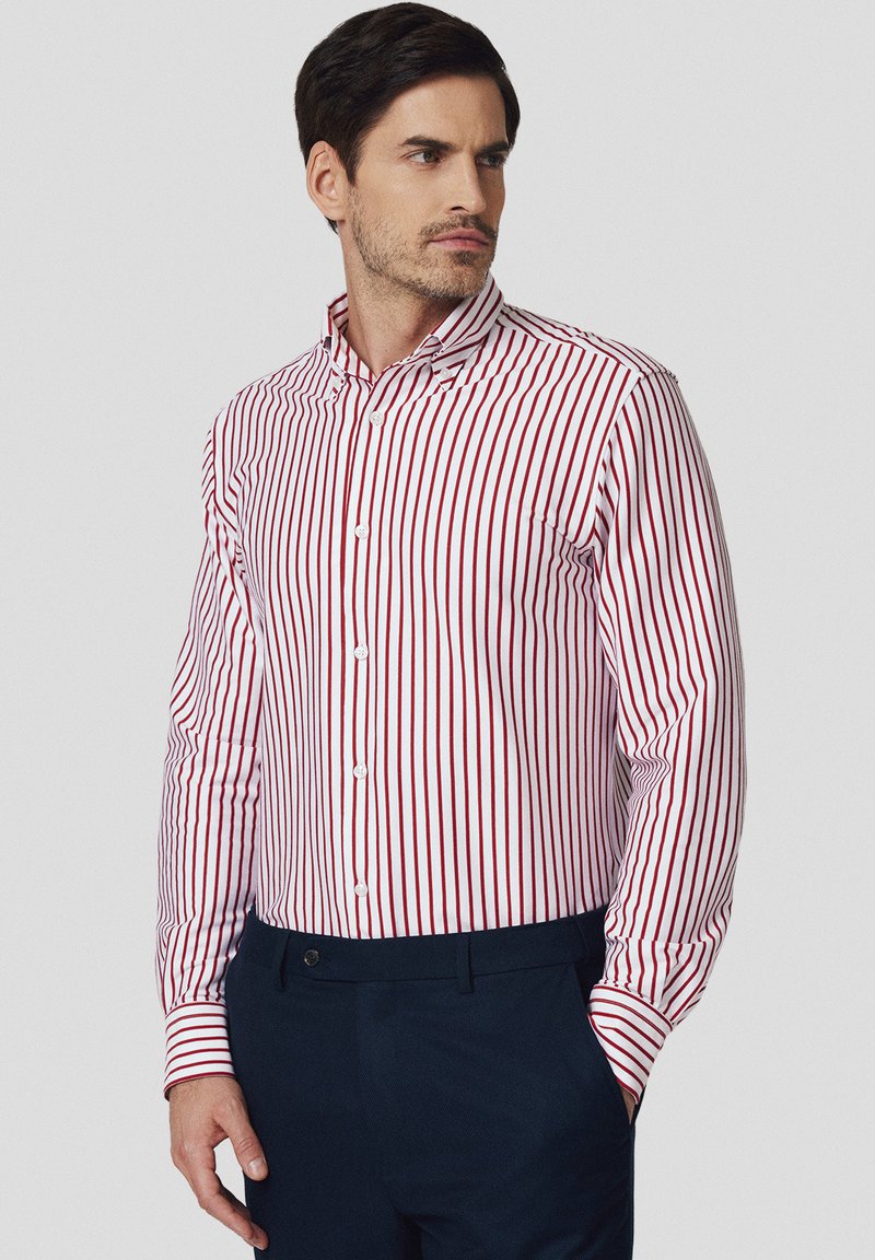 Czerwona i biała w paski koszula na guziki z długimi rękawami i spiczastym kołnierzykiem, wykonana z gładkiego materiału i dopasowanym kroju.