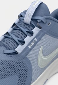 Nike atletske tenisice s gornjim dijelom od svijetloplavog mrežastog materijala, sivoj akcenti, dinamičkom tehnologijom pristajanja i reflektirajućim swoosh logotipom.