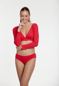 Röd bikini set med långa ärmar som har en djup V-ringning på toppen och matchande låga trosor, tillverkad i ett mjukt, elastiskt tyg.