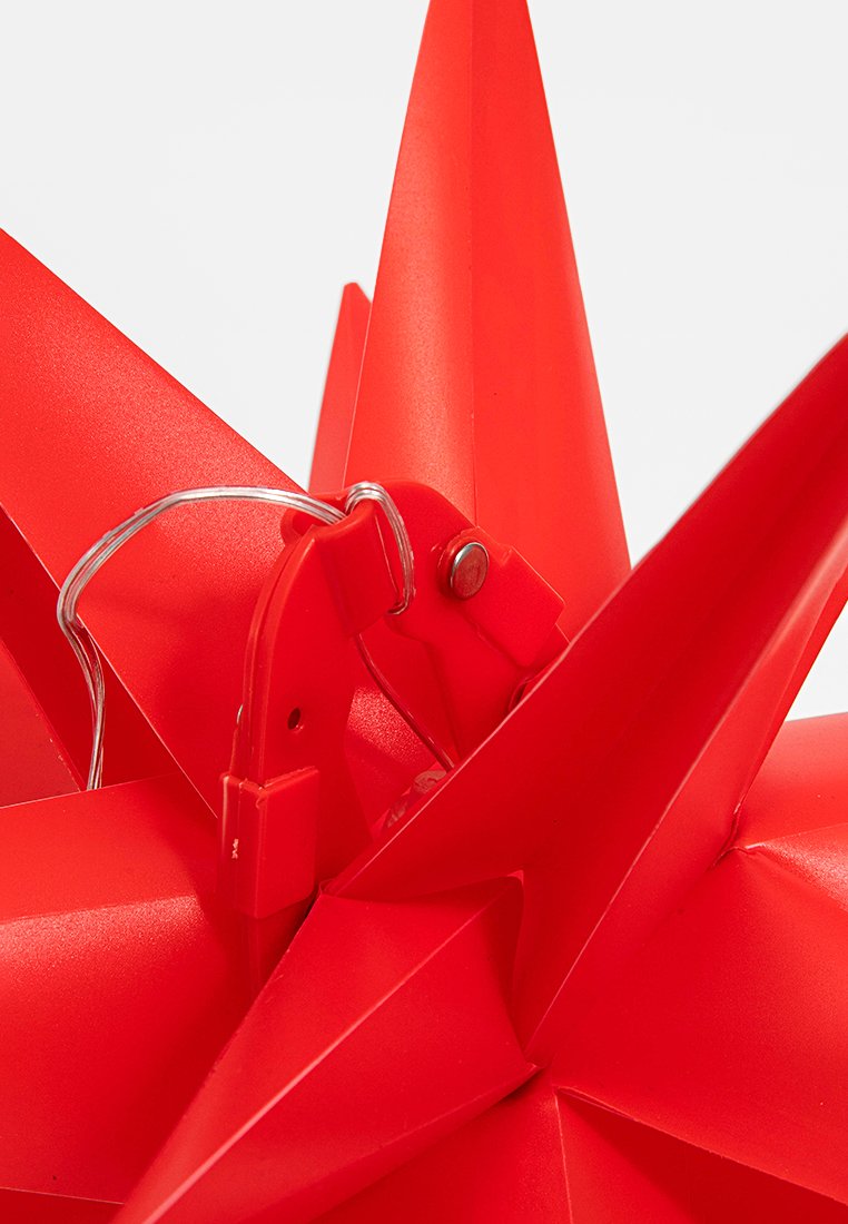 Czerwona plastikowa dekoracyjna gwiazda z ostrymi, szpiczastymi krawędziami. Zawiera metalowy haczyk i druciany zamek. Gładka powierzchnia o matowym wykończeniu.