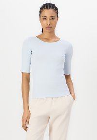Lichtblauwe ribbeltop met een ronde halslijn en mouwen tot de ellebogen, gekenmerkt door een getailleerde pasvorm en een zachte, gladde textuur.