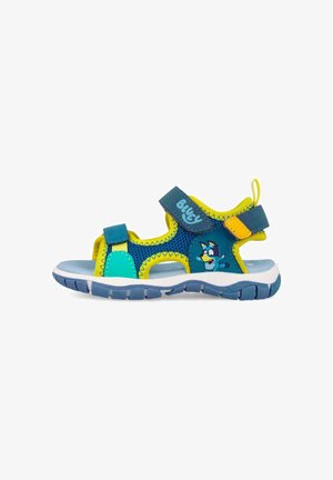 Sandalia infantil azul y amarilla con tiras de Velcro, suela flexible y personaje de perro de dibujos animados en el lateral.