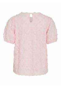 Blouse rose clair à manches courtes avec une superposition en dentelle florale texturée et une petite ouverture en forme de goutte au niveau de l'encolure arrière.