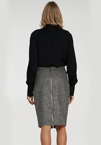 Czarna bluzka z długim rękawem zestawiona z ołówkową spódnicą do kolan w szarym kolorze, z teksturowanym wykończeniem i widocznym zamkiem z tyłu.