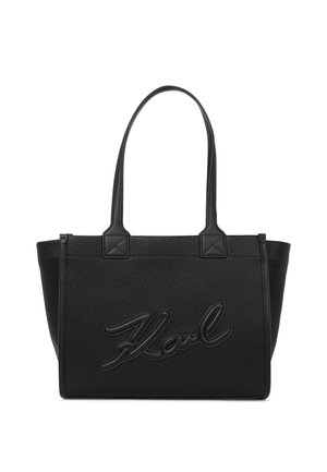 Zwarte, gestructureerde tote bag met dubbele handvatten, voorzien van reliëfmerk "Karl" aan de voorkant en hoekige accenten aan de basis van de handvatten.