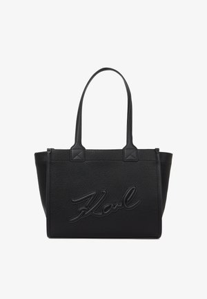 Črna torba iz teksturiranega materiala z dvema ročajema, ki na sprednji strani vključuje vtisnjeno oznako "Karl" in angularne detajle na dnu ročajev.