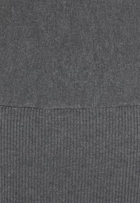 Tissu tricoté gris foncé présentant deux motifs côtelés différents séparés par une couture horizontale.