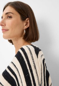 Strickpullover mit horizontalen schwarzen und cremigen Streifen, versehen mit strukturiertem Stoff und Paillettenakzenten entlang des Musters.
