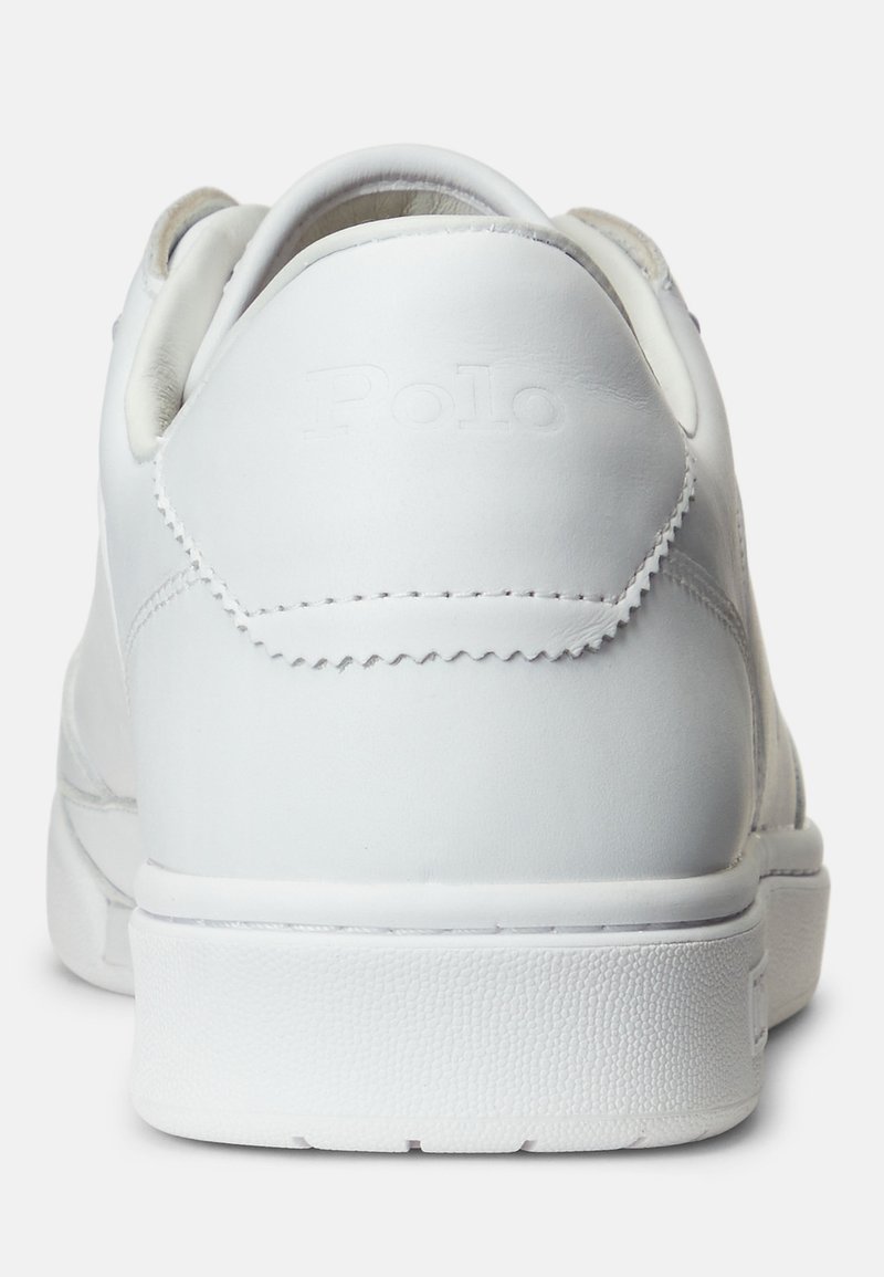 Zapatilla blanca de cuero con un acabado suave, suela de goma ligeramente texturizada y un logotipo sutil en el talón. Diseño limpio y minimalista.
