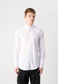 Witte langarm overhemd met een button-down kraag, zachte stof en een afgeronde zoom, gecombineerd met donkere broeken.