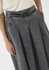 Dunkelgrau denimrock mit plissiertem Design, seitlichen Taschen und strukturiertem Finish. Taillenbund mit dezenten Nähten.