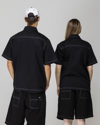 Black short-sleeve shirts with contrasting white stitching, paired with black shorts. Simple design with a relaxed fit, showcased from the back.