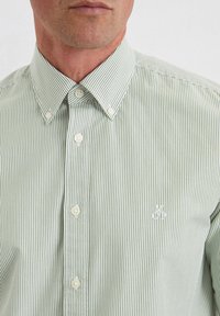 Grün-weiße gestreifte Hemd mit Knopfleiste, Stehkragen, weißen Knöpfen und einem kleinen gestickten Logo auf der Brust.