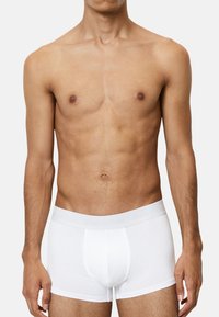 Weiße Boxershorts aus weichem Stoff mit einem schlichten Design und einem grauen, gebrandeten Bund. Der Schnitt ist eng und reicht bis zur Mitte des Oberschenkels.