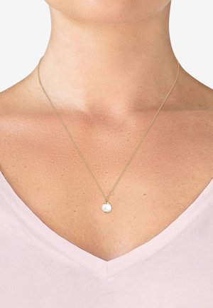 Collier en chaîne dorée avec un pendentif en perle blanche ronde, suspendu au niveau de la clavicule, porté sur un haut v-neck rose clair.