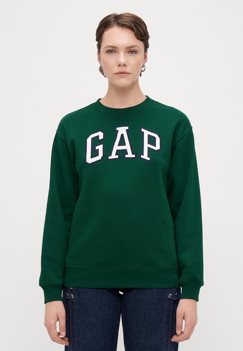 Grønn genser med ribbestrikkede mansjetter og nederkant, med fremtredende hvit "GAP" bokstaver i et kollegialt stil over brystet.