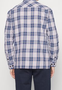 Pitkähihaisessa ruudullisessa paidassa on vaaleanharmaa tausta, sinisiä ja tummansinisiä ruutuja, nappihihansuut ja klassinen kaulus.