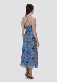 Abito maxi floreale in leggero tessuto blu, con corpetto aderente, schiena arricciata e spalline incrociate, decorato con un motivo floreale.