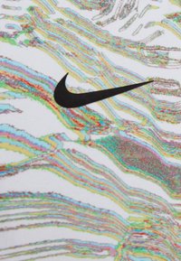 Czarne logo Nike swoosh na białej tkaninie z wielokolorowymi, abstrakcyjnymi, falującymi liniami przypominającymi anatomiczne wzory kości lub mięśni.