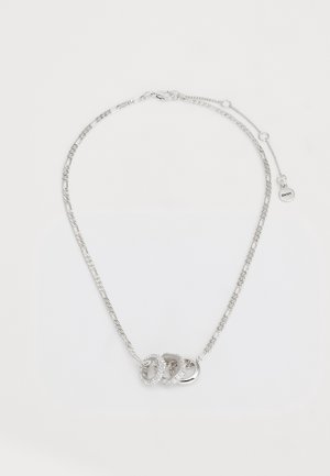 Srebrny naszyjnik z trzema połączonymi pierścieniami, z których jeden jest zdobiony małymi kryształkami, oraz regulowanym zapięciem z metką DKNY.