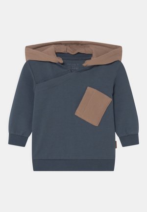 Sweat à capuche bleu foncé à manches longues avec doublure de capuche marron et poche avant inclinée marron sur le côté gauche.