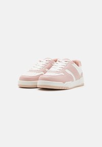 Pantofii sport au un superior din piele roz moale, accente albe și o talpă din cauciuc texturată. Design clasic cu șireturi, cu perforații pe vârf.