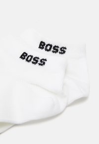 White cotton socks with a ribbed texture, featuring black "BOSS" logo embroidered on the cuffs.