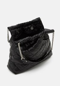 Černá prošívaná kožená kabelka přes rameno se stříbrnými řetízkami a otevřeným vrškem, ukazující magnetické zavírání a logo Valentino na přední straně.