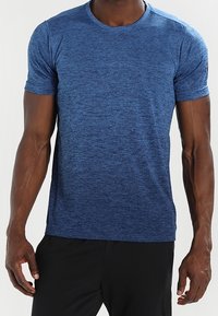 Blå kortärmad sportt-shirt gjord av strukturerad tyg med rund halsringning och subtila melerade mönster.