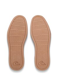 Ruskeat kumikengän pohjat, joissa on aaltoileva kuvio ja logo oikeassa alakulmassa. Suora pinta ja pyöristetyt reunat.