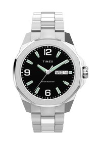 Montre en acier inoxydable argenté avec un boîtier octogonal, un cadran noir, des index horaires blancs, des accents verts et un affichage de la date, marquée "ÉTANCHÉITÉ".
