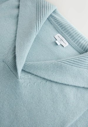 Jasnoniebieski sweter z jagnięcej wełny z teksturowanym, prążkowanym kołnierzem i mankietami, z metką oznaczoną "100% wełna jagnięca". Miękka, gładka faktura.