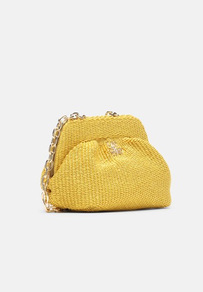 Sac à main tissé jaune avec bandoulière chaîne dorée et petite fermeture décorative dorée à l'avant, présenté sur un fond clair uni.