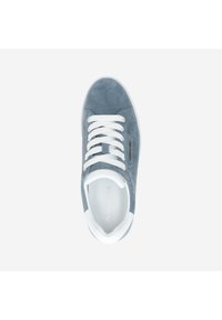 Zapatilla de ante gris con cordones blancos y suela de goma blanca. Presenta un acabado texturizado y un logo sutil en el lateral.