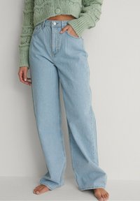 Ljusblå vida jeans med hög midja, med knappstängning, frampockets och en något slitna nederkant.