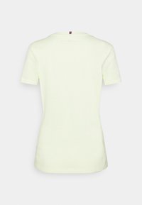 T-shirt en coton jaune clair avec un col rond et des manches courtes. Présente un petit accent rayé au niveau du col au dos. Texture lisse.