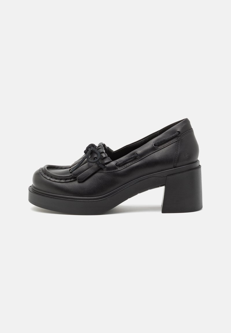Mocassin pour femme en cuir noir avec talon bloc épais, détail pompon et semelle plateforme sur fond uni clair.