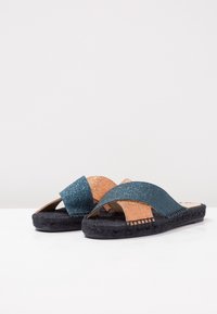 Glitrové skluzavkové sandály s teplou a měděnou barevnou kombinací, s otevřenou špičkou a pletenou jutenou podešví pro přidanou texturu.